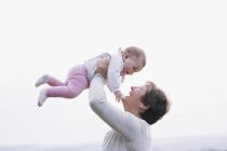 Woman holding a baby girl in the air — Stock Photo