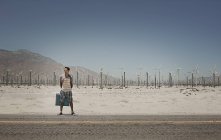 Homem com uma mala ao lado de uma estrada — Fotografia de Stock