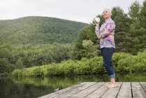 Жінка стоїть на причалі озера — стокове фото
