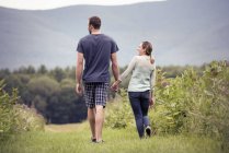 Hombre y mujer caminando a través de un prado - foto de stock