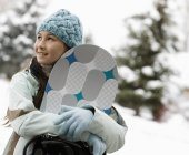 Chica con sombrero y guantes llevando una tabla de snowboard . - foto de stock
