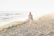Donna che cammina lungo una spiaggia sabbiosa — Foto stock