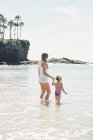 Mujer con hija en la playa . - foto de stock
