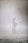 Woman flyfishing in thigh deep water. — Stock Photo