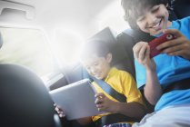 Jungen mit Tablet und Smartphone im Auto — Stockfoto