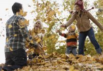 Familia jugando en otoño hojas . - foto de stock