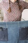 Женщина держит и заворачивает джинсовый фартук — стоковое фото