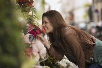 Mujer doblando para oler el aroma de las flores - foto de stock