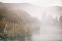 Женщина рыбачит, стоя на берегу реки . — стоковое фото