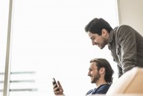 Zwei Geschäftsleute schauen aufs Smartphone — Stockfoto