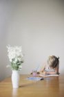 Молода дівчина сидить за столом, малює — стокове фото