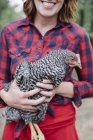 Woman holding a grey hen — Stock Photo
