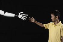 Boy reaching up to robotic hand. — Stock Photo
