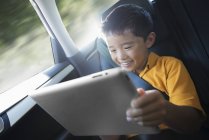 Мальчик с цифровым планшетом в машине — стоковое фото