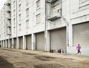Femme courant le long d'une route urbaine — Photo de stock