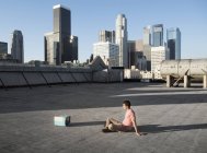 Homem sentado em um telhado da cidade — Fotografia de Stock