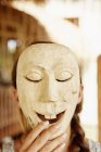 Person holding up a wooden mask — Stock Photo