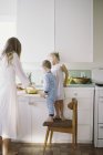 Жінка з дітьми стоїть на кухні — стокове фото