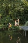 Мальчики прыгают с причала в воду — стоковое фото