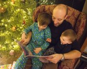 Homme lisant le livre à deux enfants — Photo de stock