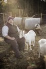 Bauer tätschelt weiße Ziege. — Stockfoto