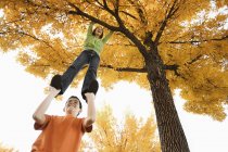 Boy and girl under autumn tree — Stock Photo