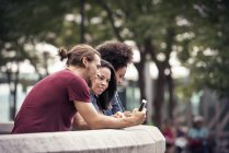 Hombre y dos mujeres usando teléfonos inteligentes - foto de stock