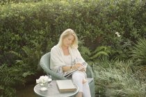 Donna seduta in un giardino — Foto stock