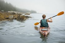 Hombre remando un kayak en aguas tranquilas - foto de stock
