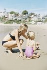 Mujer en bikini jugando con su hija - foto de stock