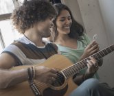 Чоловік грає на гітарі і жінка з телефоном — стокове фото