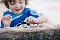 Niño en la playa contando conchas - foto de stock