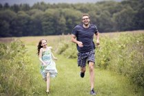Man and child running through meadow — Stock Photo