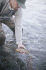 Pescatore con in mano un piccolo pesce — Foto stock
