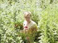Jovem mulher de pé em um viveiro de plantas — Fotografia de Stock
