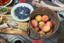 Picnic table with basket of fresh peaches — Stock Photo