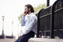 Man seated on a step making a call — Stock Photo