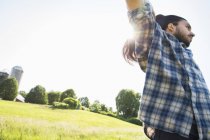 Young man raising arms in the field — Stock Photo