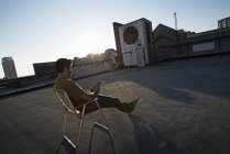 Homem sentado em uma cadeira de praia no telhado — Fotografia de Stock