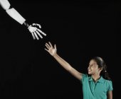 Girl reaching up to robotic hand. — Stock Photo