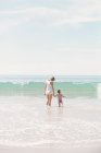 Woman with daughter watching a wave. — Stock Photo