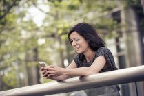 Жінка чіпляється за мобільний телефон у парку — стокове фото