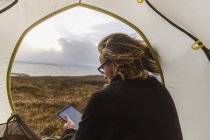 Homme dans la tente tenant une tablette numérique — Photo de stock