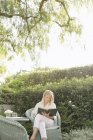 Жінка сидить в саду, читаючи — стокове фото