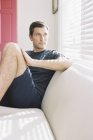 Man sitting on a sofa by a window — Stock Photo