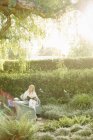Женщина, сидящая в саду и читающая — стоковое фото