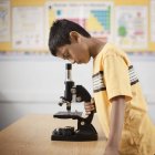 Niño usando un microscopio - foto de stock