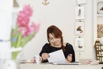 Frau sitzt am Schreibtisch und erledigt Papierkram — Stockfoto