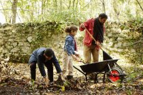 Family raking and scooping up leaves — Stock Photo