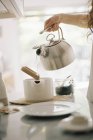 Pouring hot water into a tea pot. — Stock Photo